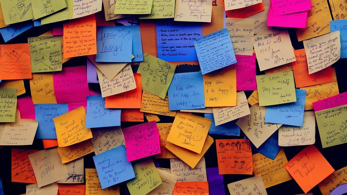 Team grouping sticky notes on a wall to sort user interview findings into themes